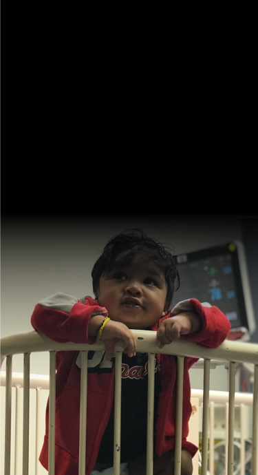 SickKids patient Maxen standing up in his crib at the hospital