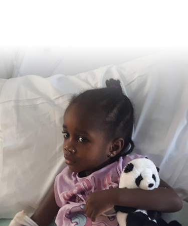 A photo of SickKids Patient Maya in her hospital bed holding a toy
