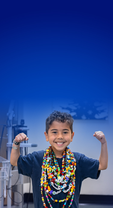 Caleb at SickKids, smiling with his arms in a strong pose.