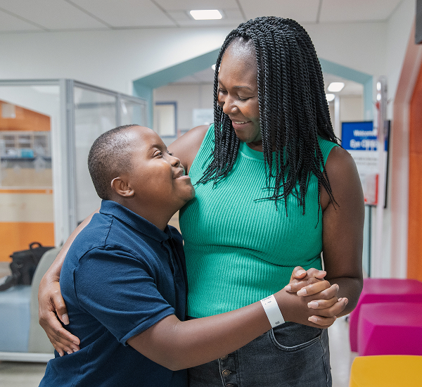 Malcolm holding hands with and hugging his mom at SickKids.