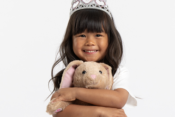 Layla, smiling. She is wearing a tiara and hugging a stuffed bunny. 