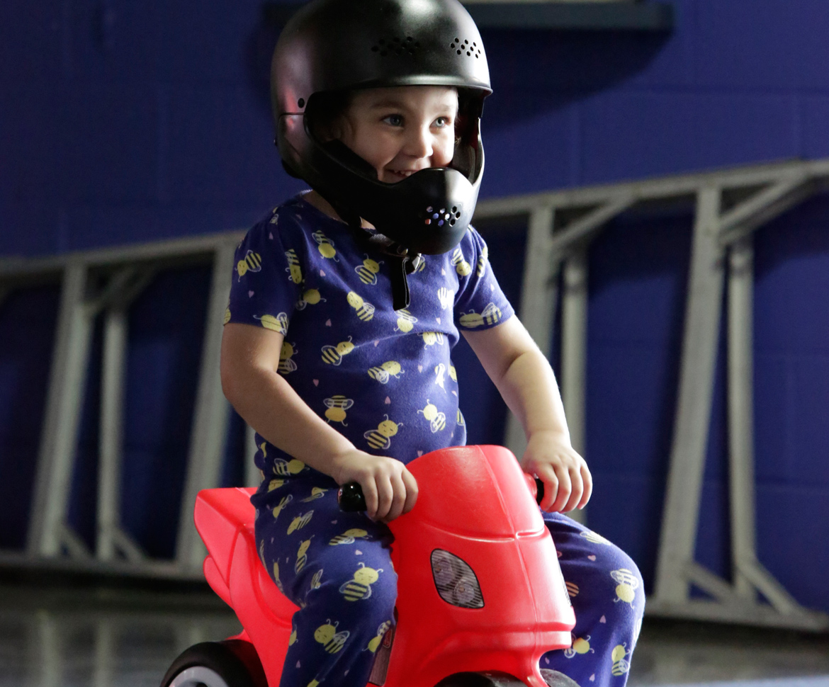 Child on toy motorcycle with helmet