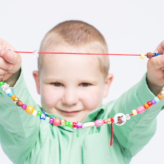 Boy holding up Bravery Bead necklace