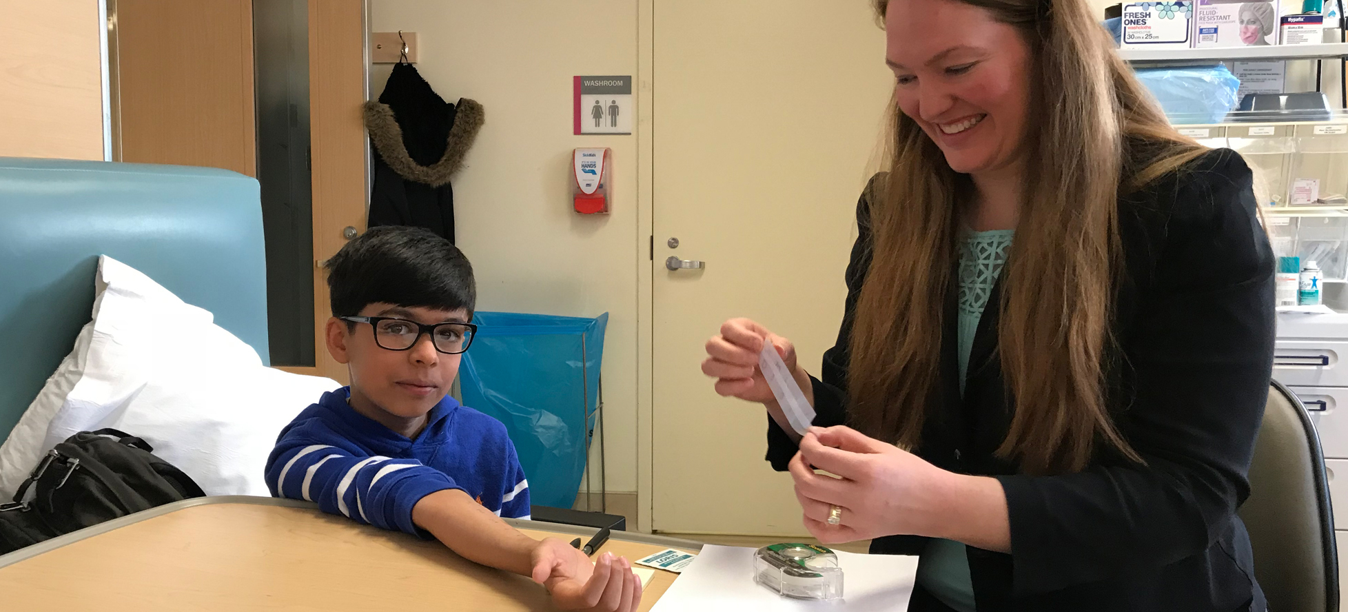 Child with arm out and nurse holding bandaid