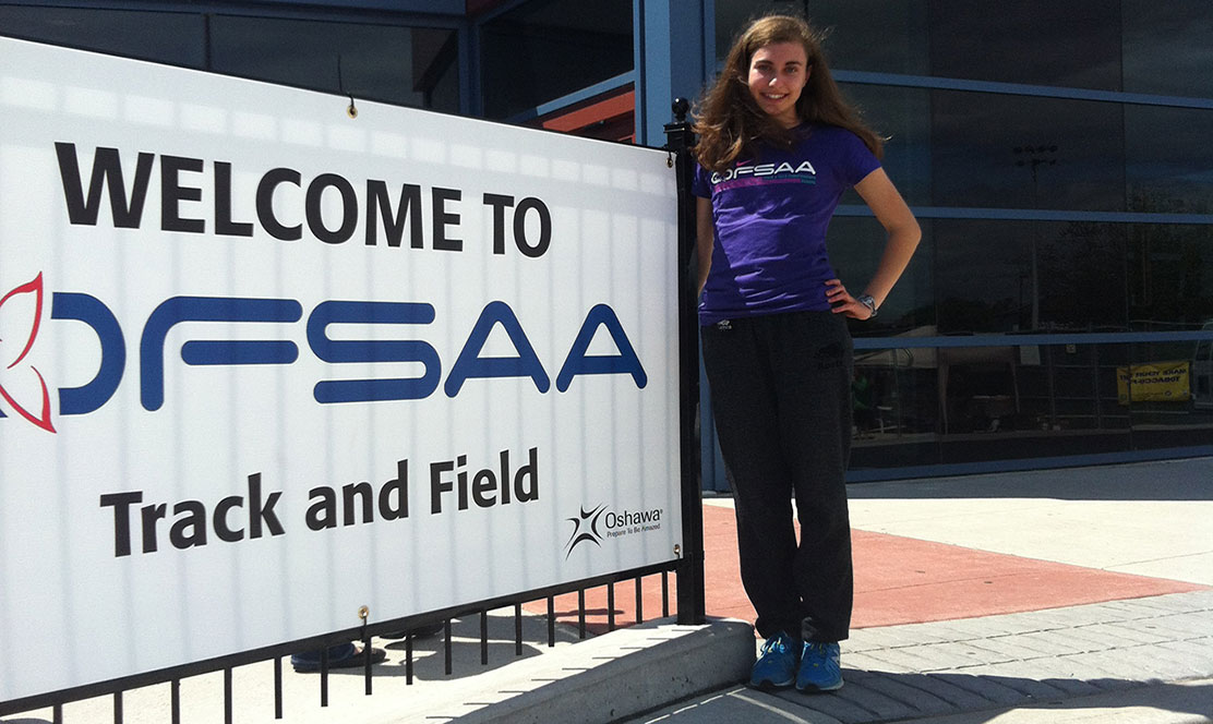 Photo of SickKids patient Sarah in front of OFSAA Track and Field sign