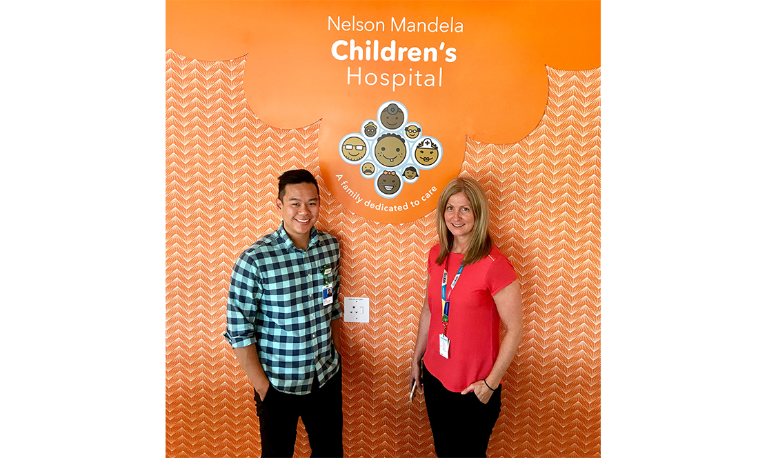 Man and woman standing below Nelson Mandela Children's Hospital logo