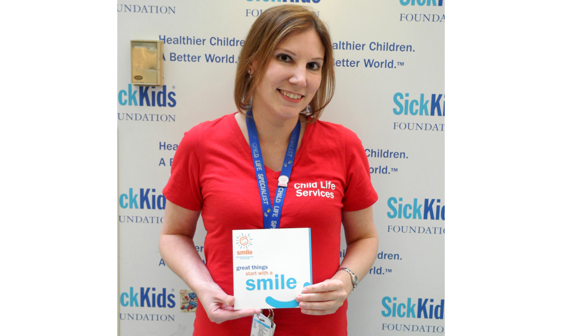 SickKids staff member holding a smile award card