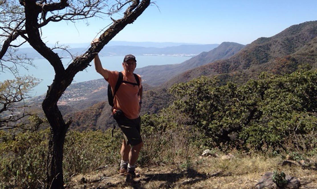 Man on top of mountain by a tree