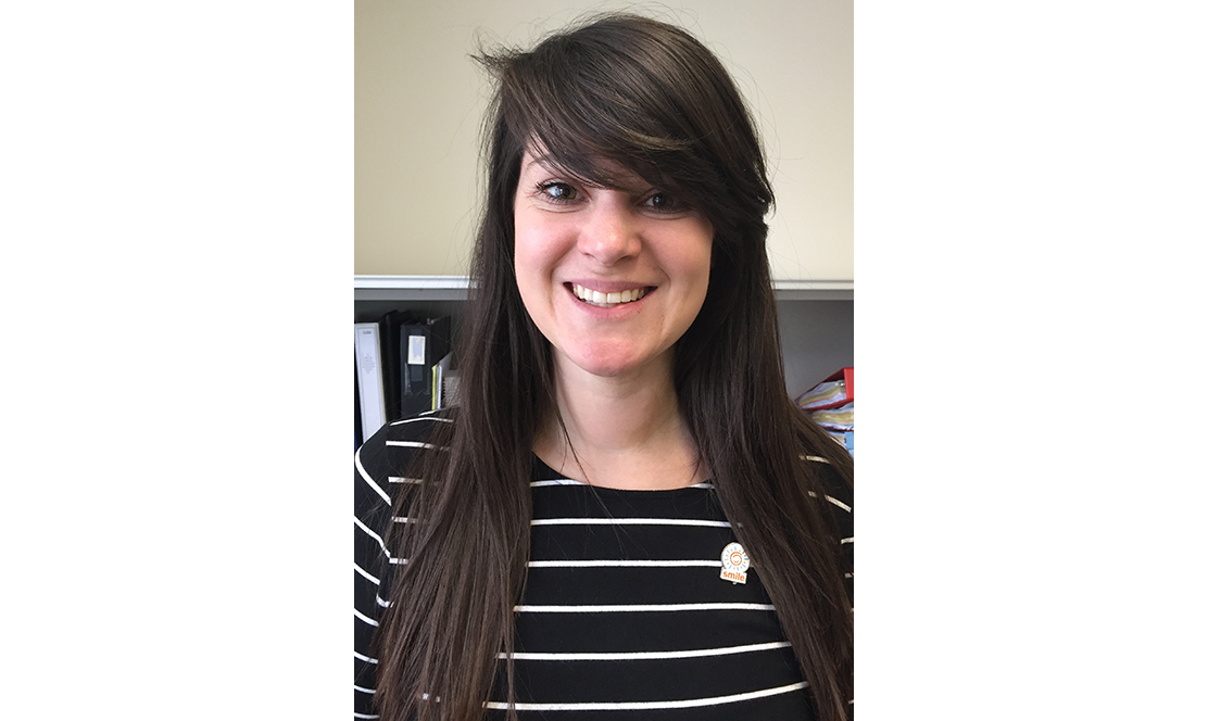 Girl wearing SMILE pin and smiling