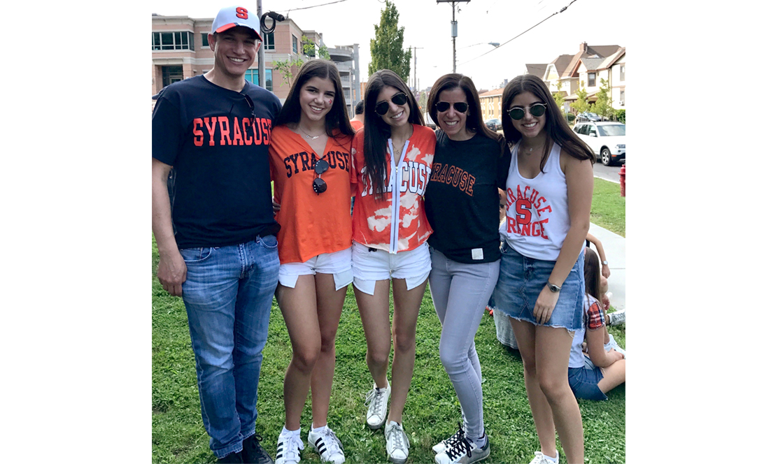 Mom and dad with their three daughters standing together smiling