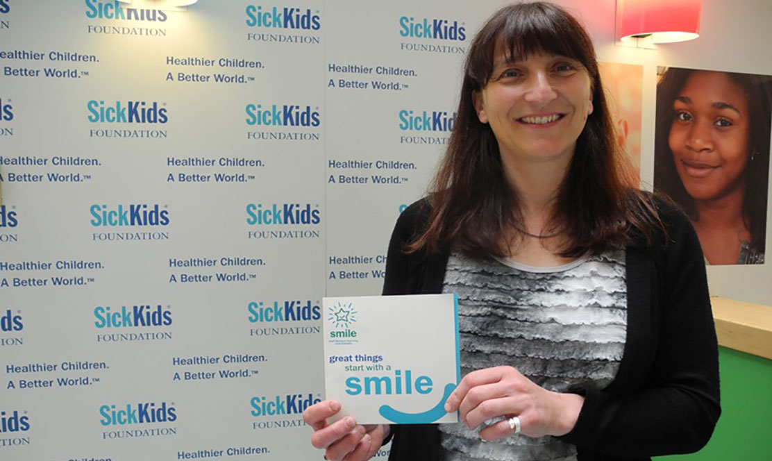 SickKids staff member holding a SMILE card