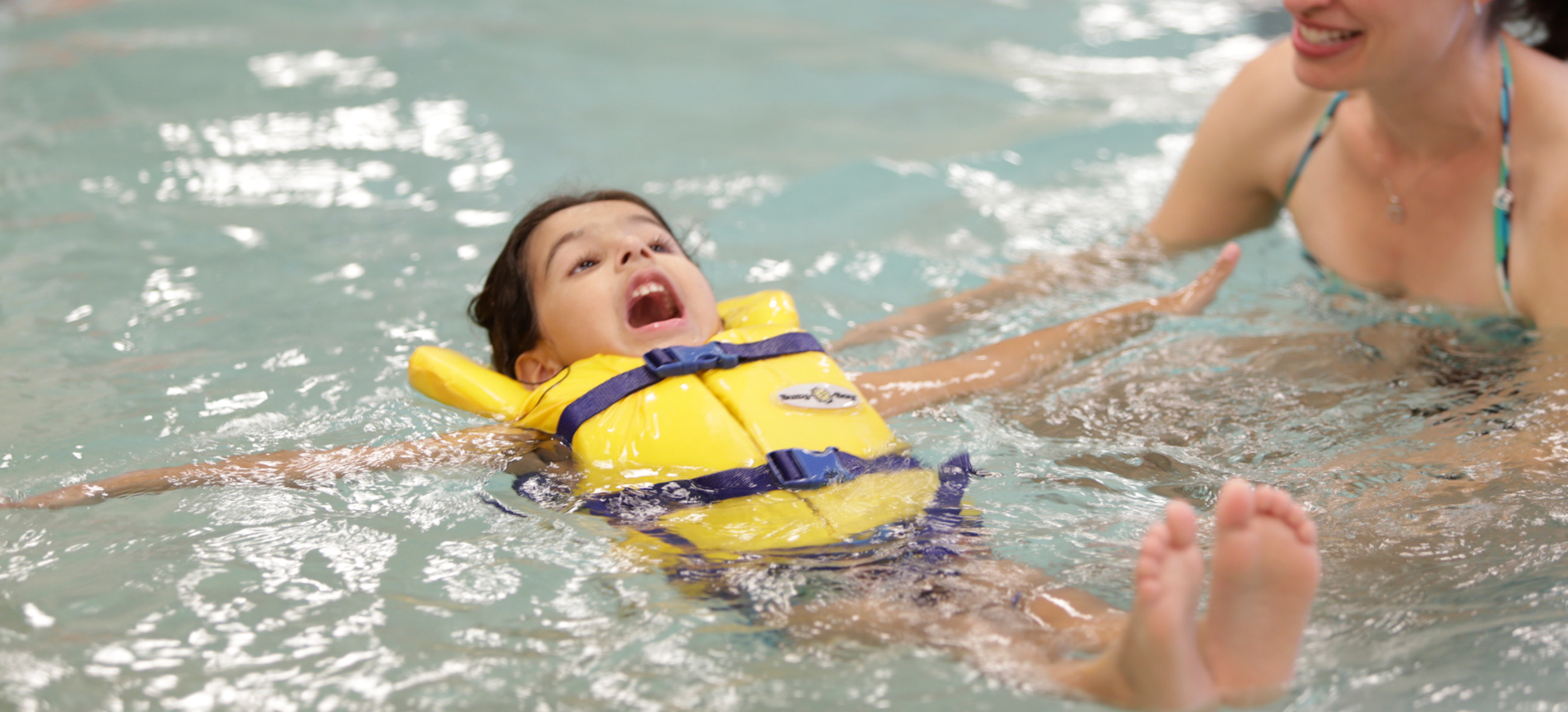 Little girl doing a backfloat in a pool with life jacket on