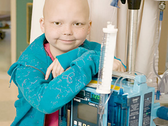 Bald girl leaning on IV pole