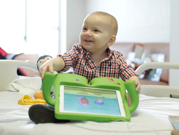 Little boy in plaid shirt with toy on hospital bed