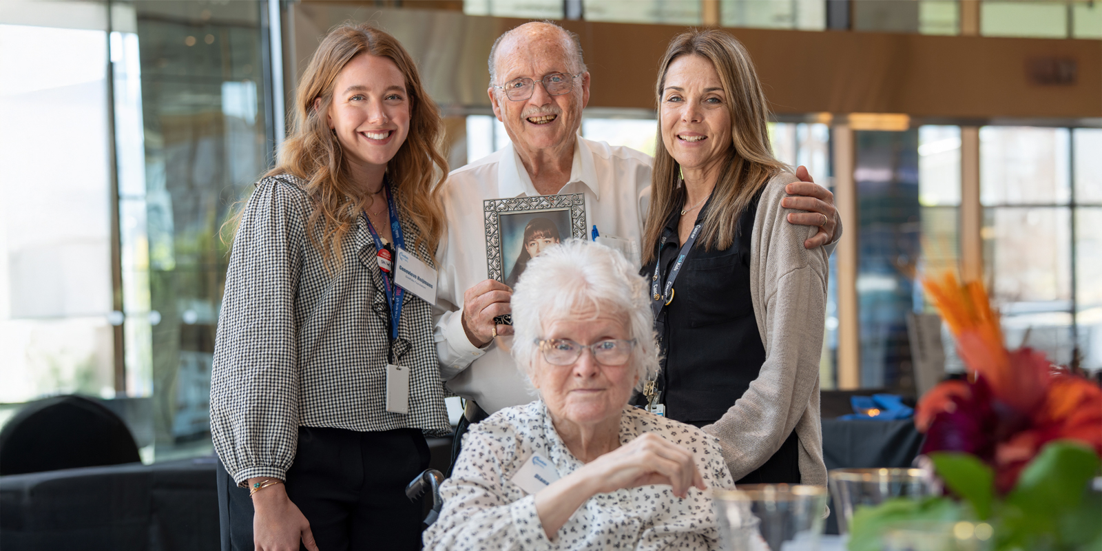 A donor couple hold up a picture of their daughter, accompanied by SickKids staff.