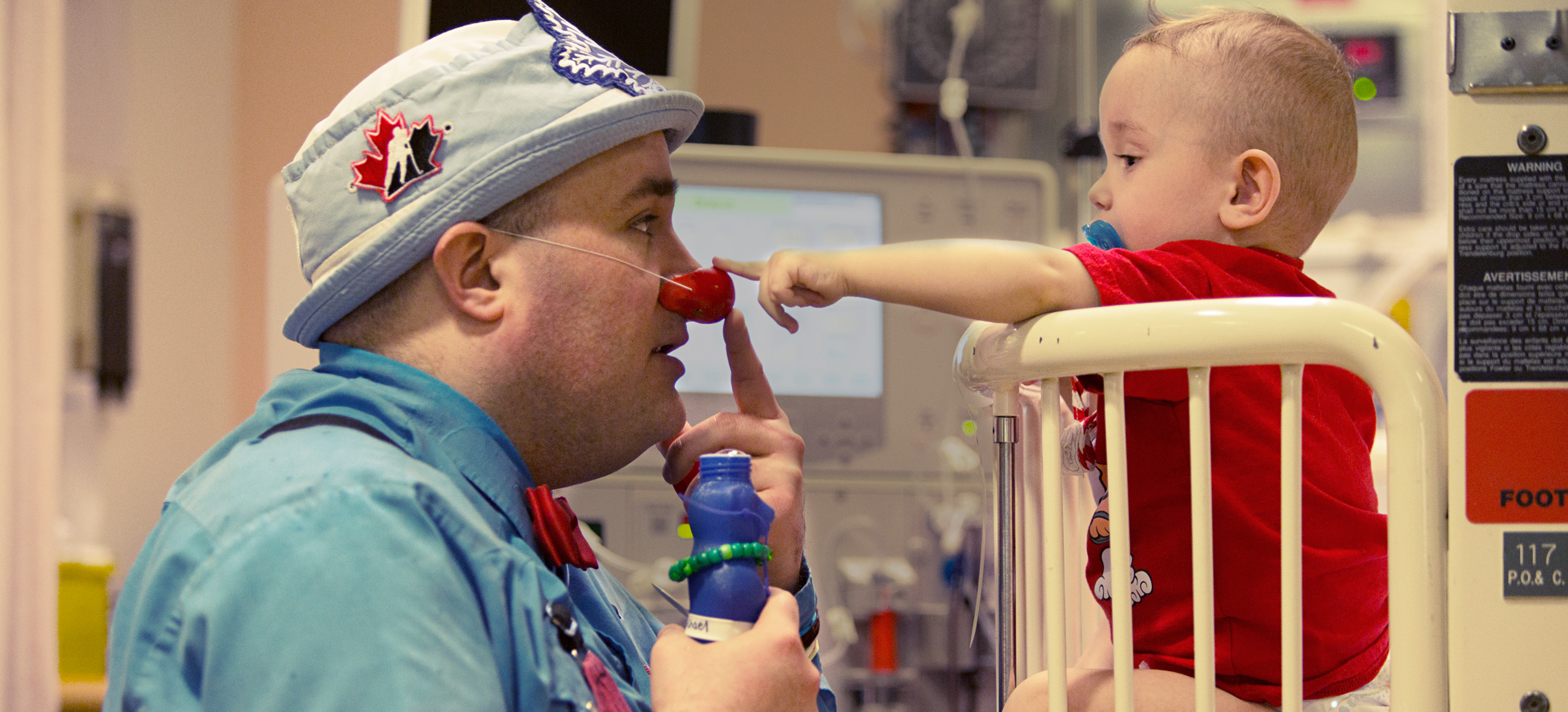 A Le Boo, therapeutic clown, talking to baby in crib