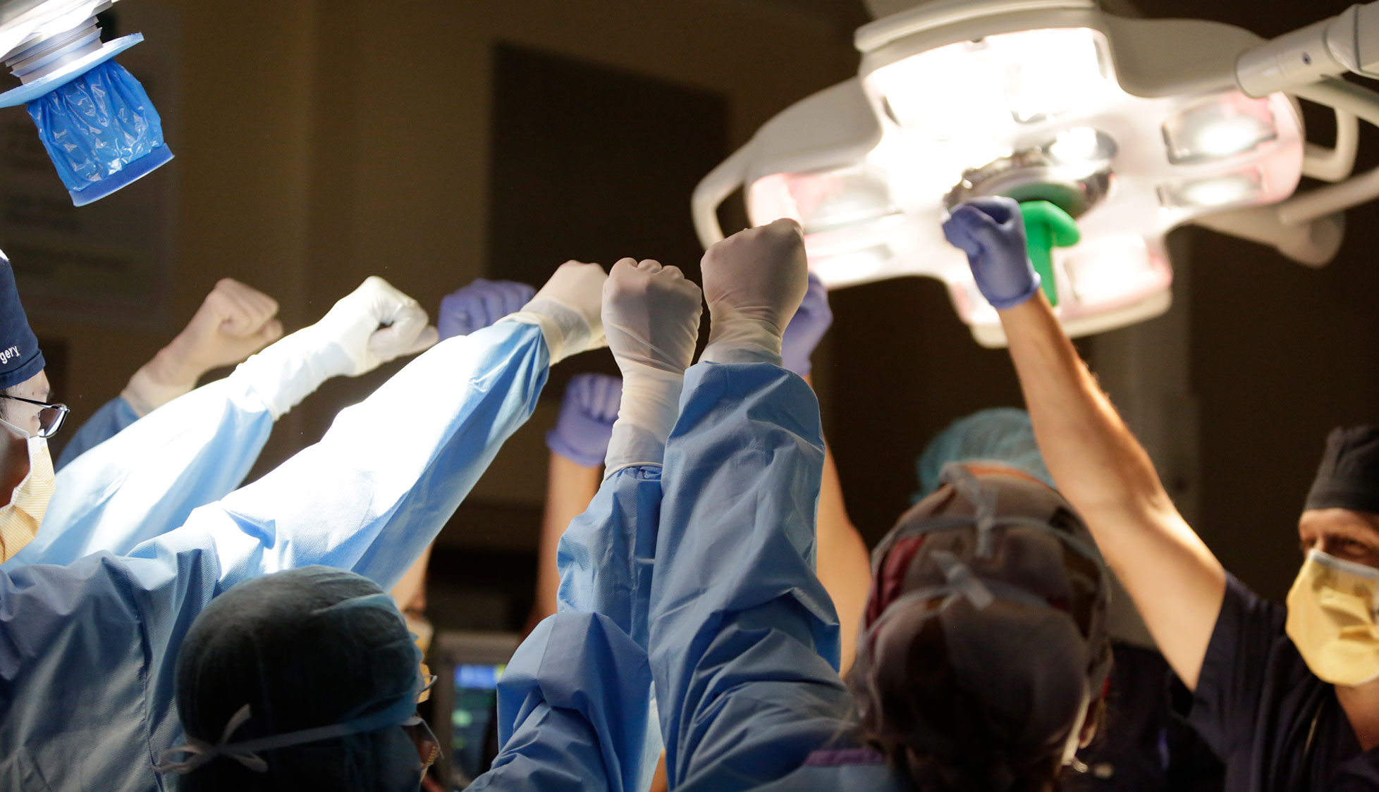 Doctors in operating room with hands raised